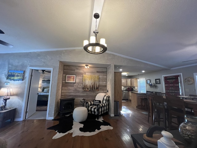 dining space with a wood stove, a ceiling fan, lofted ceiling, and dark wood-style floors