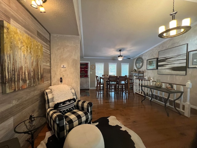 living room with lofted ceiling, a textured ceiling, ceiling fan with notable chandelier, crown molding, and dark hardwood / wood-style flooring