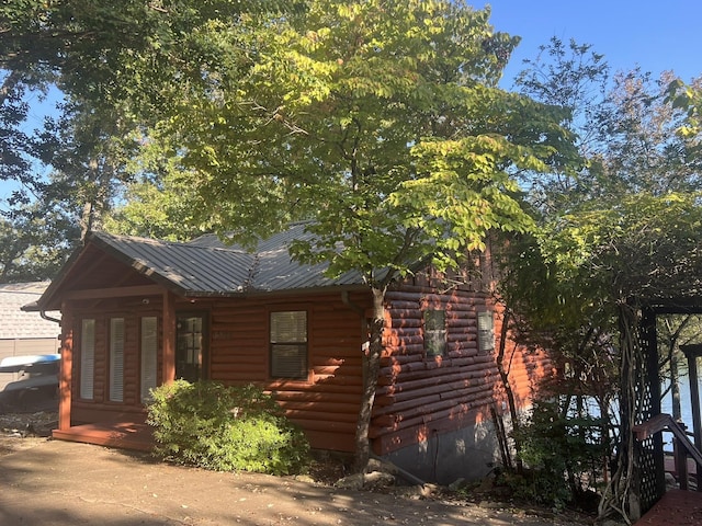 view of side of home featuring log exterior and metal roof