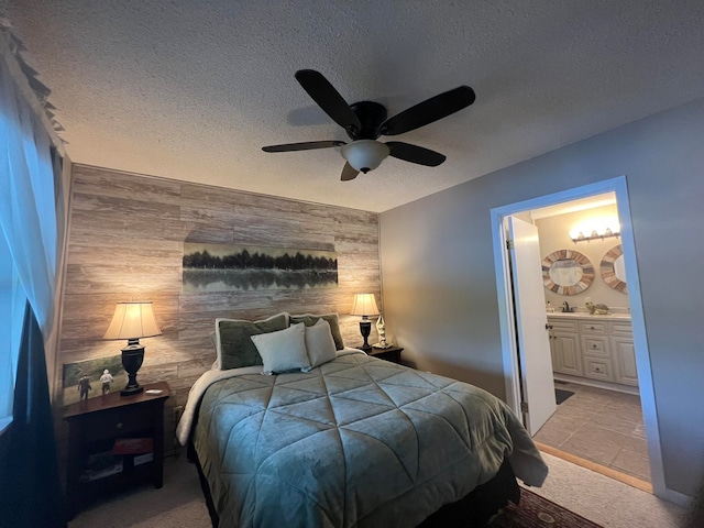 carpeted bedroom featuring wooden walls, ceiling fan, ensuite bathroom, and a textured ceiling