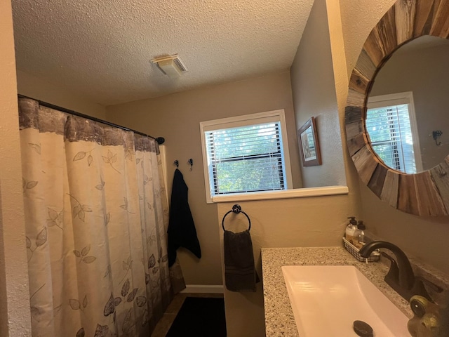 bathroom with vanity, a textured ceiling, and walk in shower