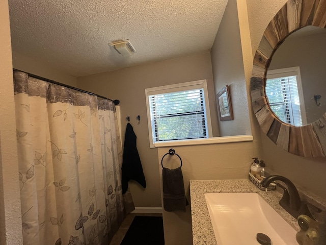 full bathroom featuring visible vents, a sink, a textured ceiling, and curtained shower