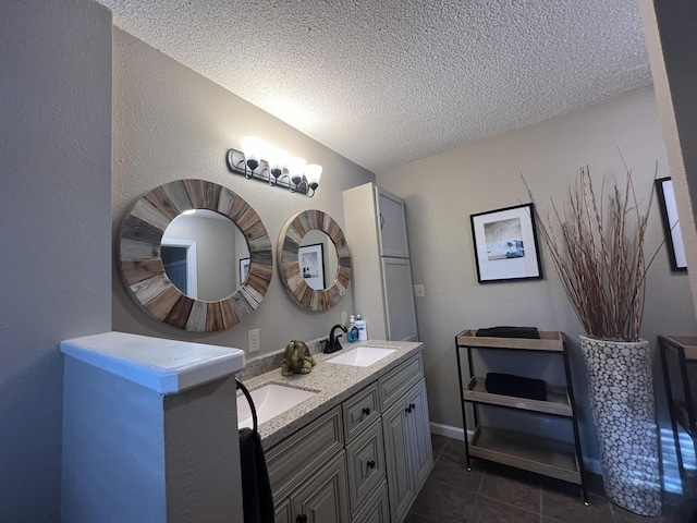 bathroom featuring double vanity, a textured ceiling, a sink, and tile patterned flooring