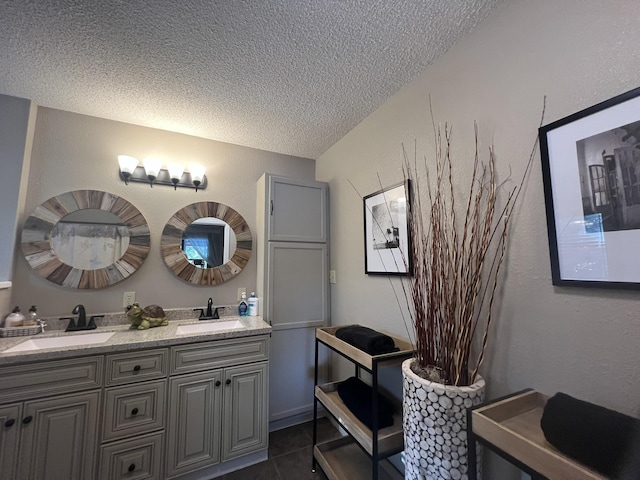 bathroom with double vanity, a sink, a textured ceiling, and tile patterned floors