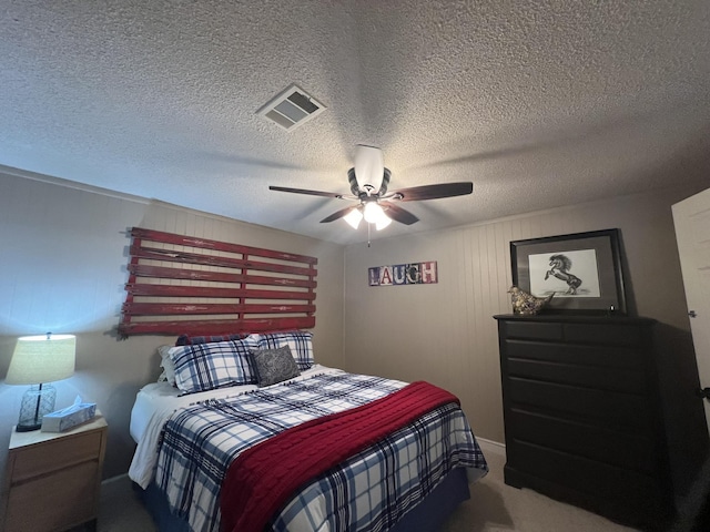 bedroom with a textured ceiling, ceiling fan, visible vents, and carpet
