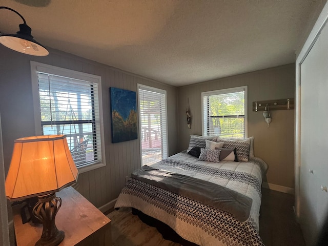 bedroom with a textured ceiling, wood walls, and a closet