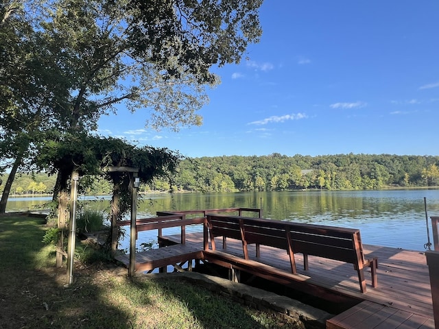 view of dock with a water view and a forest view