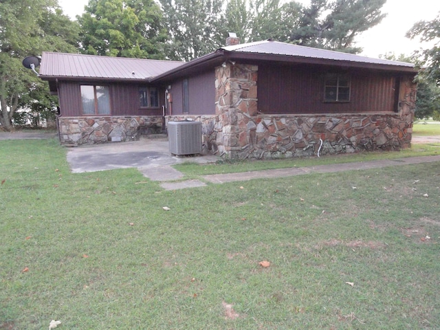 rear view of property featuring cooling unit and a lawn