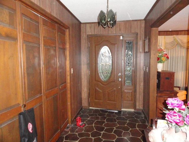 foyer entrance with wooden walls and crown molding