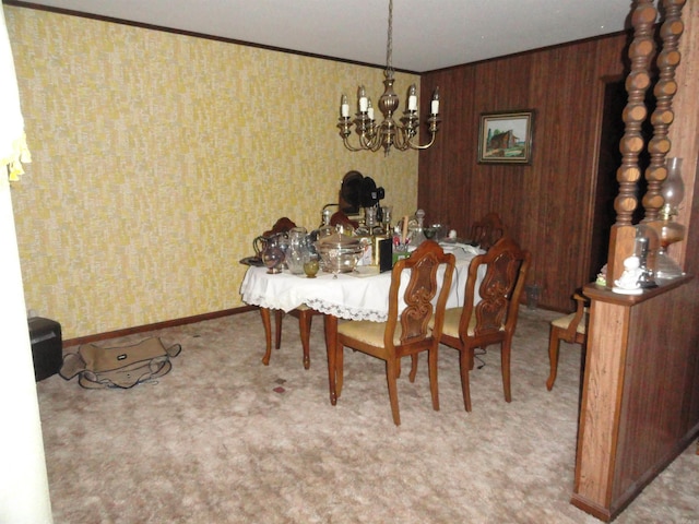 dining space featuring wood walls, a chandelier, and crown molding