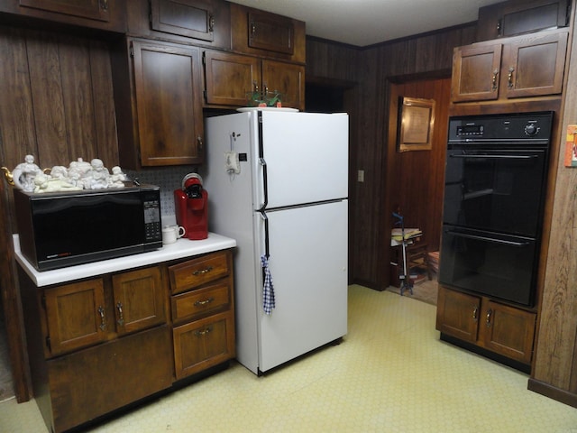 kitchen with dark brown cabinets, wooden walls, and black appliances