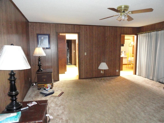 living room with ceiling fan, wooden walls, and carpet