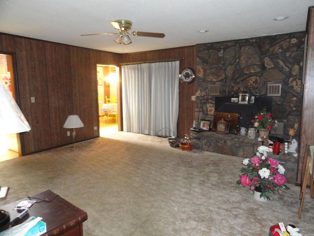 living room featuring carpet, ceiling fan, wood walls, and a fireplace