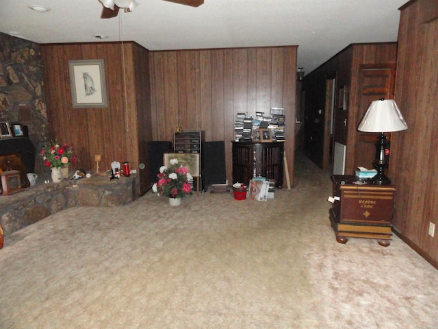 carpeted living room featuring wood walls and ceiling fan