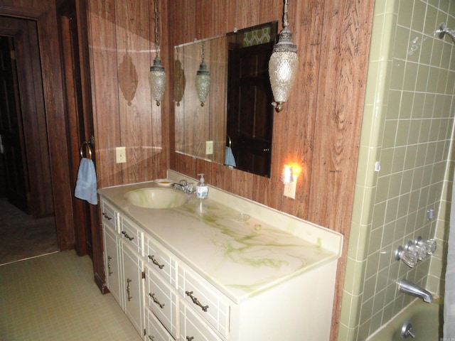 bathroom featuring wooden walls, vanity, and tiled shower / bath