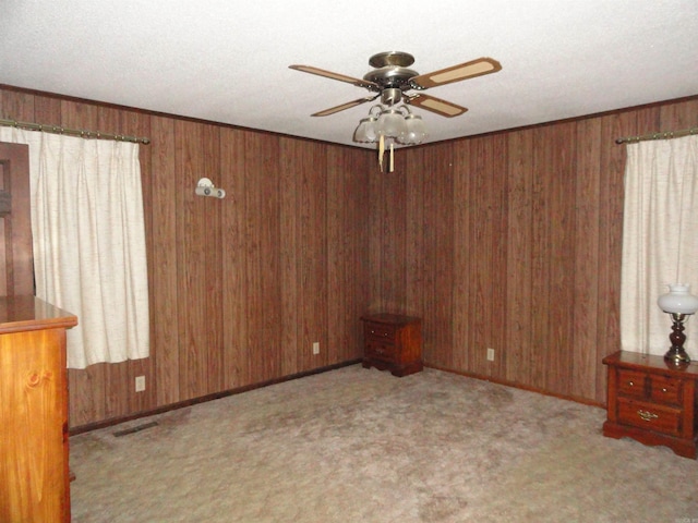 spare room with ceiling fan, light colored carpet, and wood walls