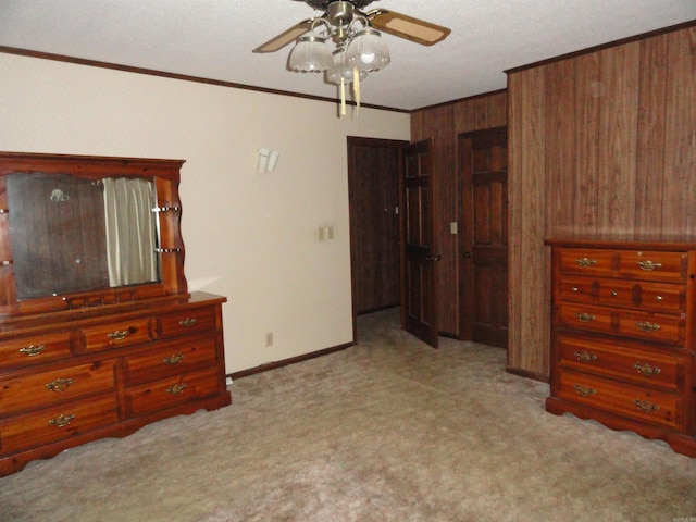 carpeted bedroom with a textured ceiling, ornamental molding, wood walls, and ceiling fan