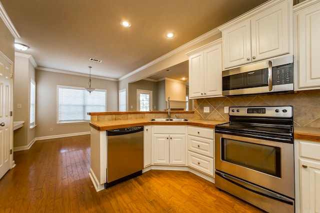 kitchen with pendant lighting, light wood-type flooring, sink, kitchen peninsula, and stainless steel appliances