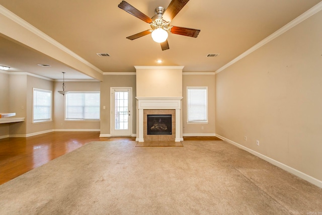 unfurnished living room with ceiling fan, light hardwood / wood-style floors, ornamental molding, and a tile fireplace