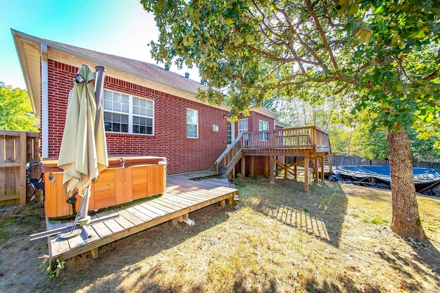 rear view of property featuring a hot tub and a deck