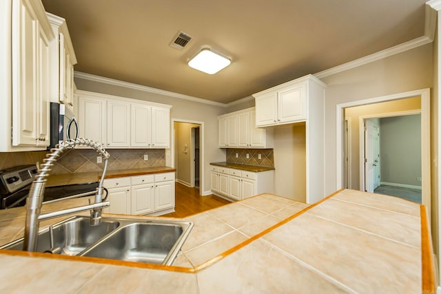 kitchen featuring white cabinets, sink, tasteful backsplash, and tile countertops