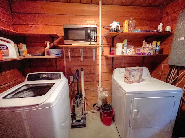 laundry area with wood walls and washer and clothes dryer