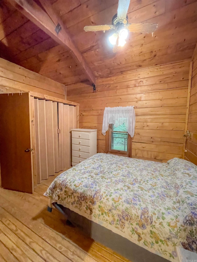 bedroom with wood-type flooring, beam ceiling, ceiling fan, and wood walls