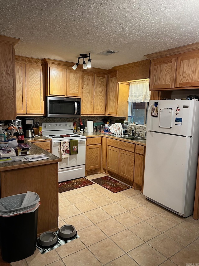 kitchen with sink, light tile patterned floors, white appliances, a textured ceiling, and backsplash