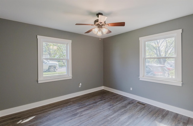 spare room with dark hardwood / wood-style flooring, ceiling fan, and a wealth of natural light