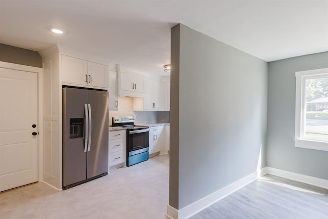 kitchen featuring appliances with stainless steel finishes, white cabinetry, and light hardwood / wood-style flooring