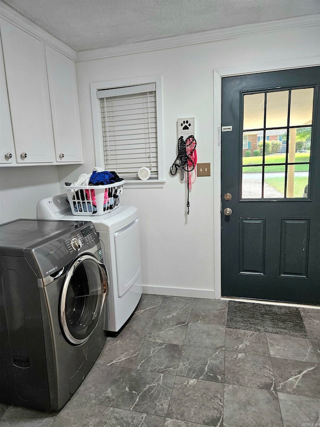 laundry room with a textured ceiling, crown molding, washer and dryer, and cabinets