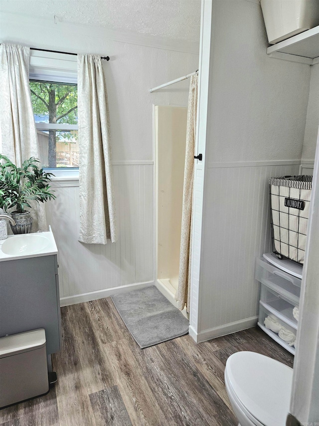 bathroom featuring curtained shower, vanity, a textured ceiling, hardwood / wood-style floors, and toilet