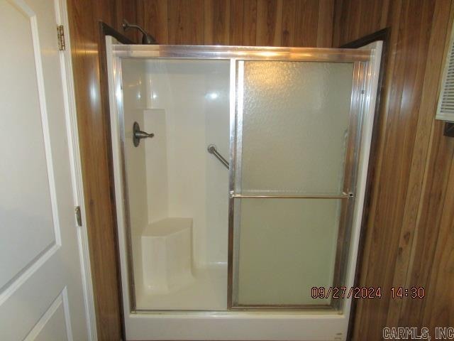 bathroom featuring wood walls and a shower with shower door