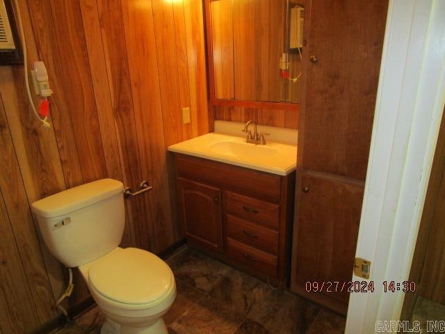 bathroom featuring wooden walls, vanity, and toilet