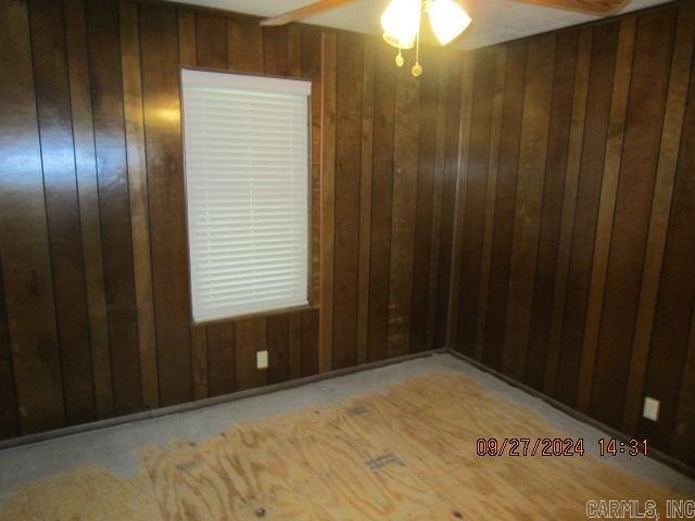 unfurnished room featuring wood walls and ceiling fan