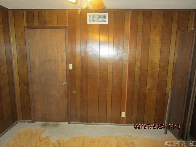 empty room featuring wood walls and ceiling fan