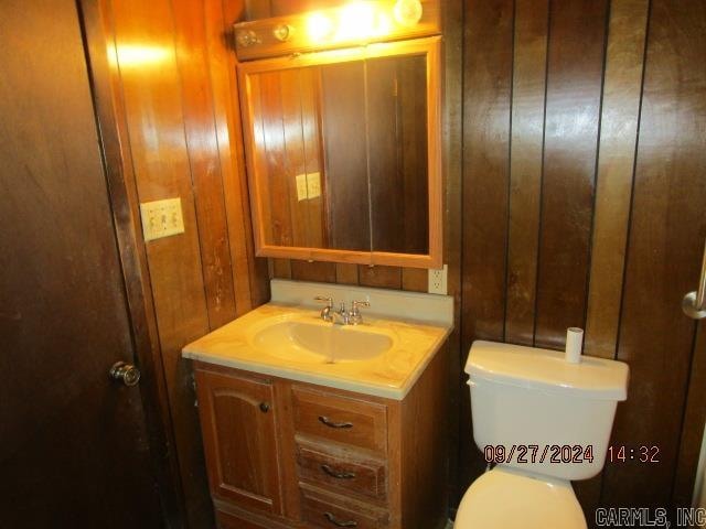 bathroom featuring wood walls, vanity, and toilet