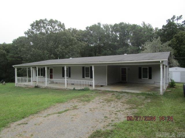 view of front of home featuring covered porch, a front lawn, and a storage unit