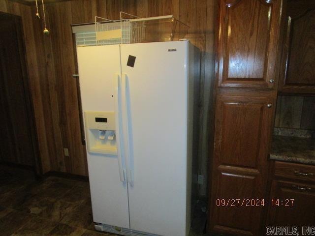 interior space featuring wood walls and white refrigerator with ice dispenser