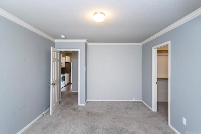 unfurnished bedroom with light carpet, a closet, ornamental molding, and a spacious closet