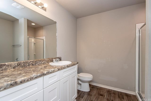 bathroom featuring hardwood / wood-style floors, walk in shower, vanity, and toilet