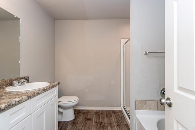 full bathroom featuring plus walk in shower, hardwood / wood-style flooring, vanity, and toilet