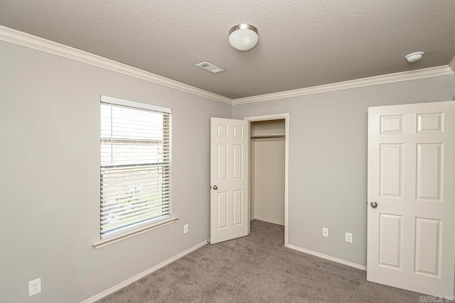 unfurnished bedroom featuring a textured ceiling, ornamental molding, light colored carpet, and a closet