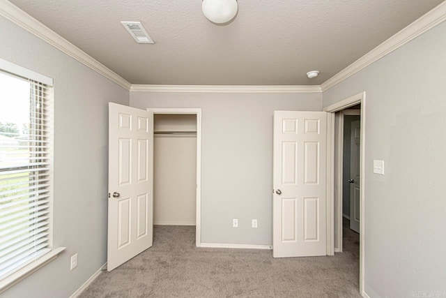 unfurnished bedroom with light carpet, a closet, ornamental molding, and a textured ceiling