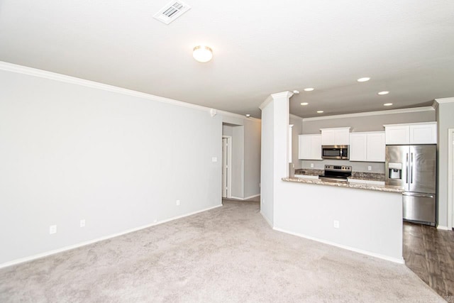 kitchen featuring ornamental molding, white cabinetry, light carpet, stainless steel appliances, and light stone countertops