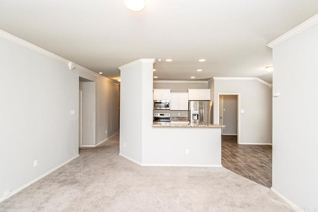 kitchen featuring appliances with stainless steel finishes, ornamental molding, light colored carpet, and white cabinets