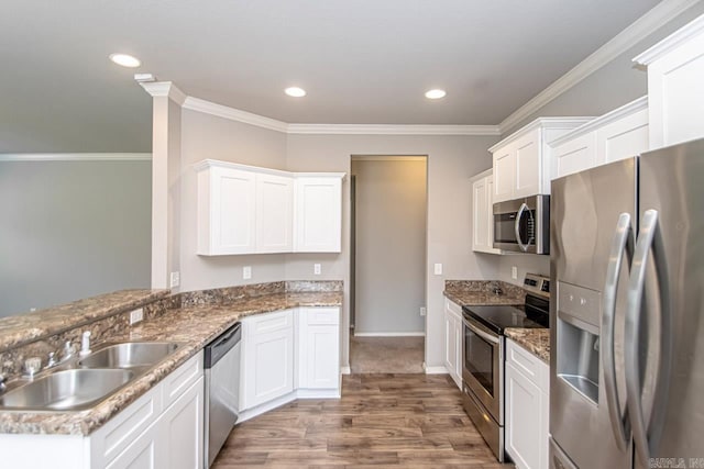 kitchen with white cabinets, sink, ornamental molding, stainless steel appliances, and light hardwood / wood-style floors