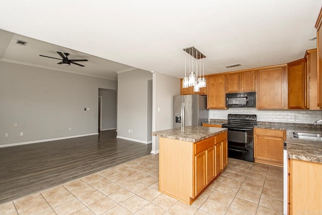 kitchen with hanging light fixtures, ceiling fan with notable chandelier, a kitchen island, black appliances, and light hardwood / wood-style flooring