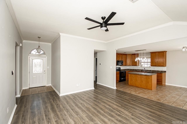 kitchen with pendant lighting, dark wood-type flooring, ceiling fan with notable chandelier, a kitchen island, and black appliances