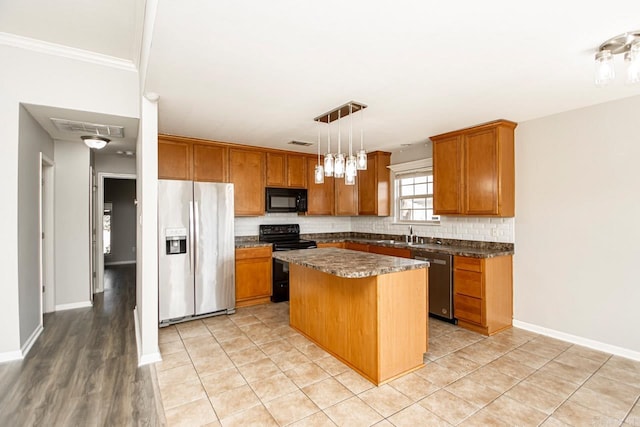 kitchen featuring light hardwood / wood-style floors, a center island, a breakfast bar area, black appliances, and decorative light fixtures